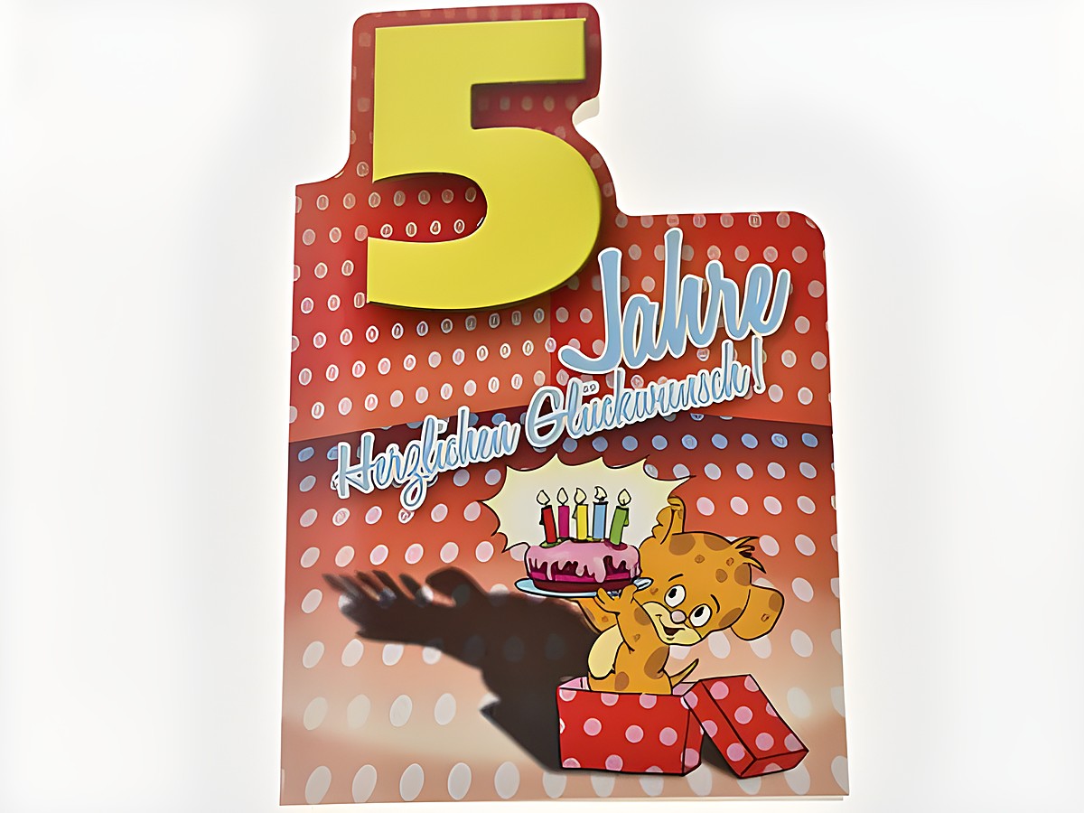 Geburtstagskarte mit einem fröhlichen Bärchen, das eine Torte mit Kerzen auf einem roten Hintergrund mit weißen Punkten präsentiert. Die Karte ist für einen fünften Geburtstag gestaltet. Hersteller: Juwelier Harnisch.