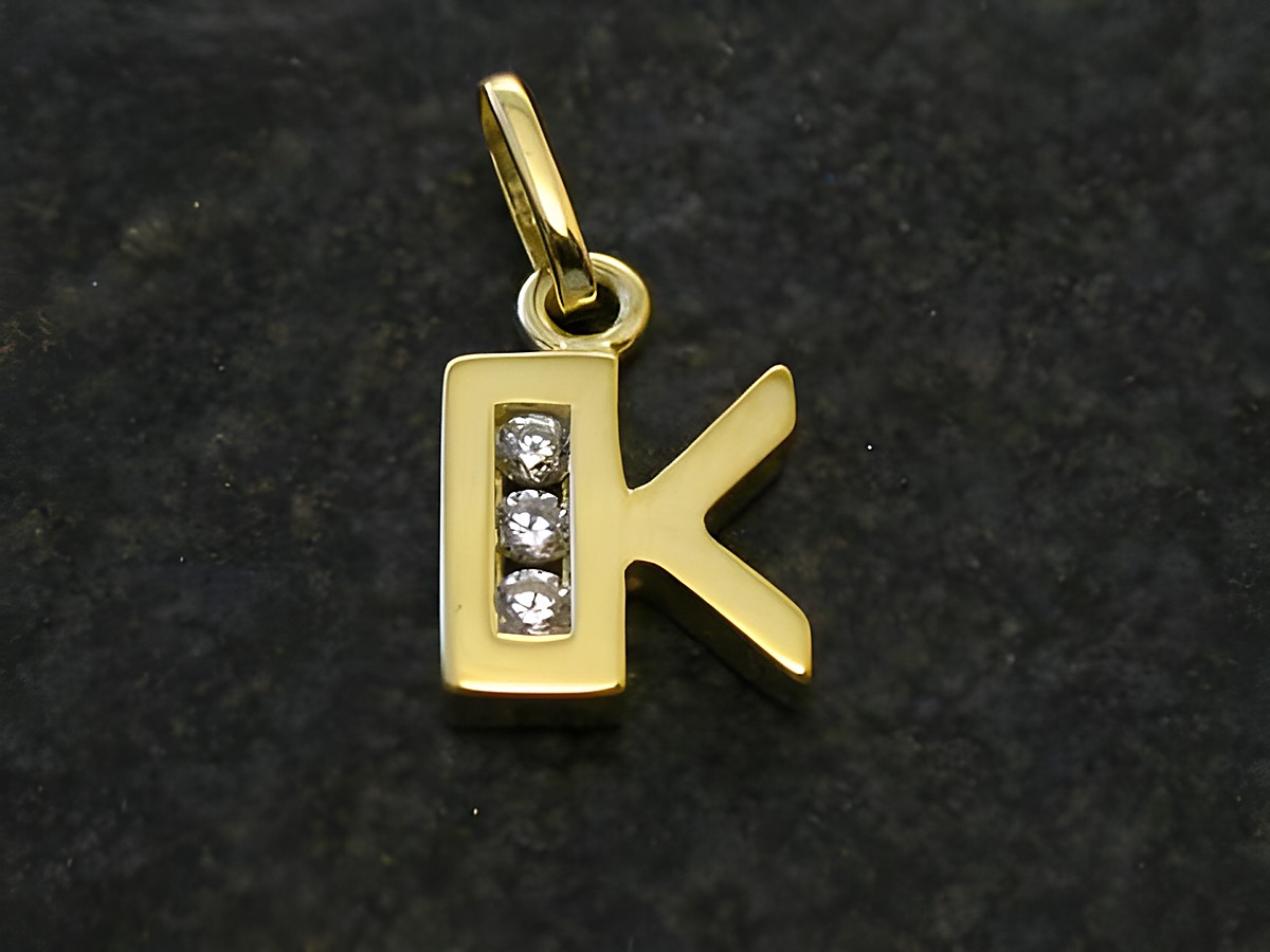 Goldener Anhänger in Form des Buchstabens K mit drei Zirkonia, hergestellt von Juwelier Harnisch. Ideal als Geschenk oder persönliches Schmuckstück.