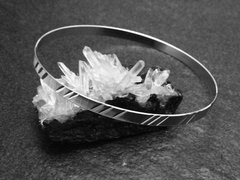 Silber Armreifen Diamantschliff aus den 70er Jahren mit einer Breite von 4,2 mm und einer Länge von 20 cm, Hersteller Juwelier Harnisch, elegant auf Kristallen präsentiert.