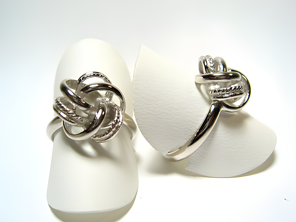 Designer Silber Ring rhodiniert in Knotenform ohne Stein, Hersteller Juwelier Harnisch, elegant präsentiert auf einem weißen Ringpolster.