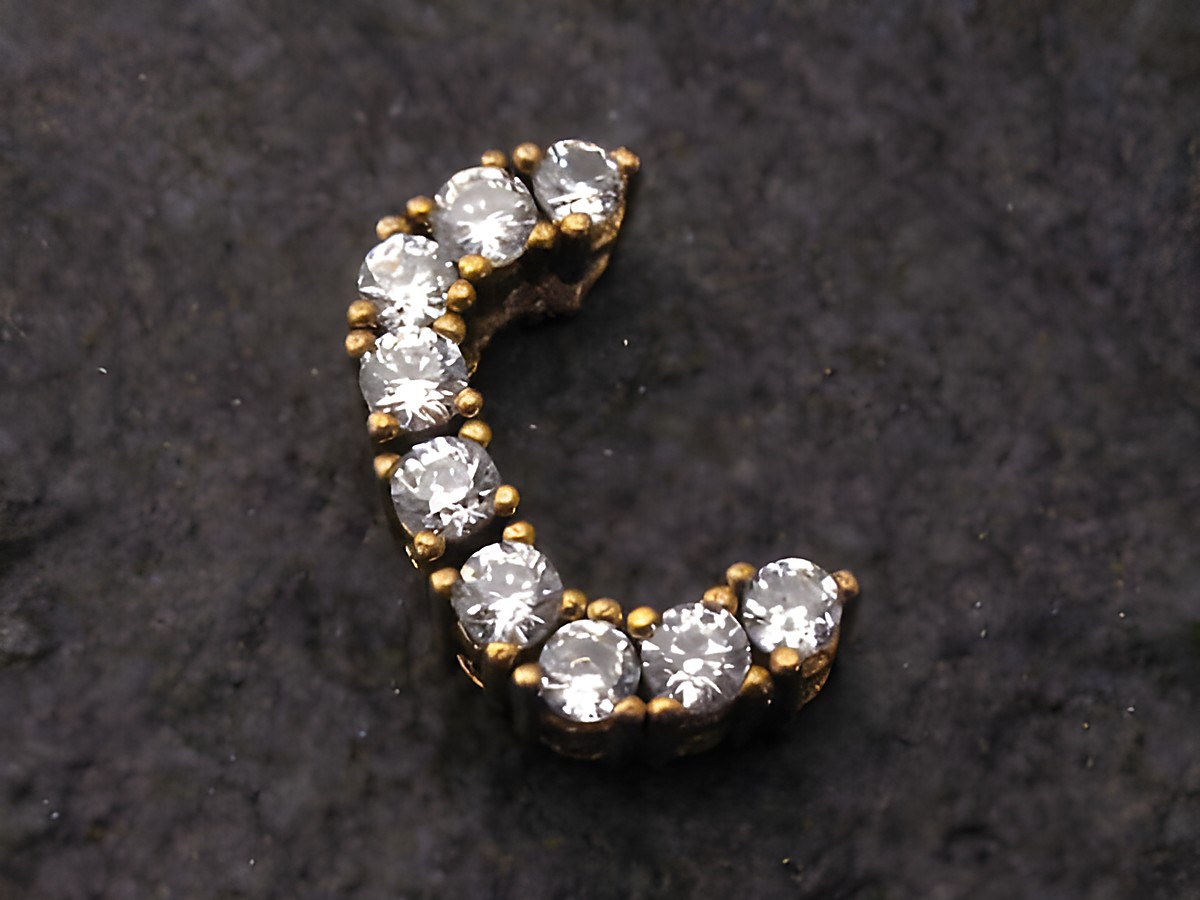C Gold Buchstaben Anhänger mit Initialen C, verziert mit Zirkonia, hergestellt von Juwelier Harnisch. Elegantes Design auf schwarzem Hintergrund, ideal für persönliche Schmuckstücke.