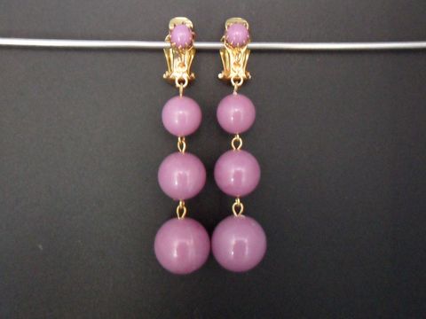 71884-0 Violette Ohrclips aus Kunstharz mit goldfarbenen Akzenten, gefertigt von Juwelier Harnisch. Zeitloses Design mit zwei hängenden Kugeln in verschiedenen Größen. Ideal für elegante Anlässe.