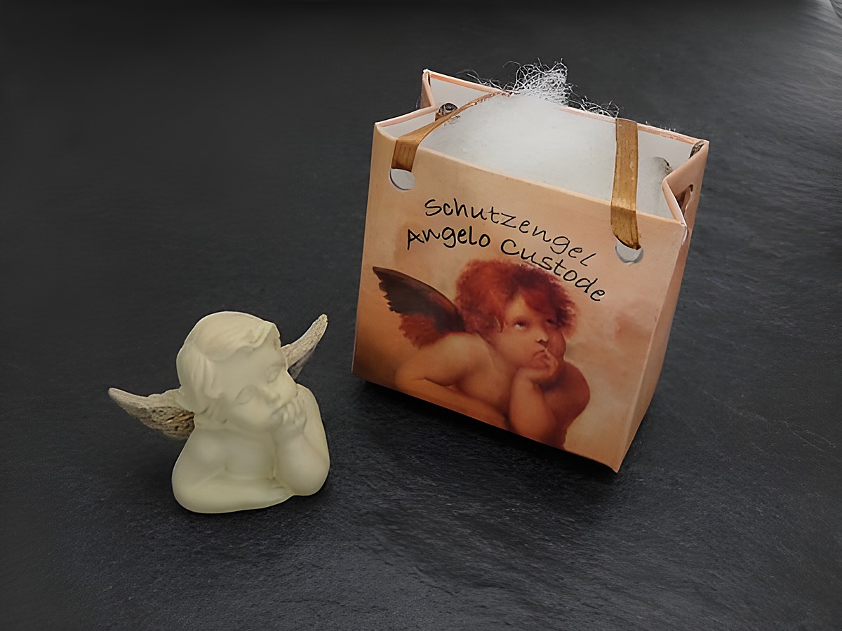 Ein nachdenklicher Schutzengel mit Geschenktasche von Juwelier Harnisch, ideal für Weihnachten, verleiht dem Bild eine festliche und besinnliche Atmosphäre.