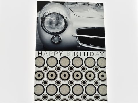 Geburtstagskarte mit einer schwarz-weißen Darstellung der Front eines Autos, verziert mit Glitzerelementen und der Aufschrift Happy Birthday, Hersteller Juwelier Harnisch.