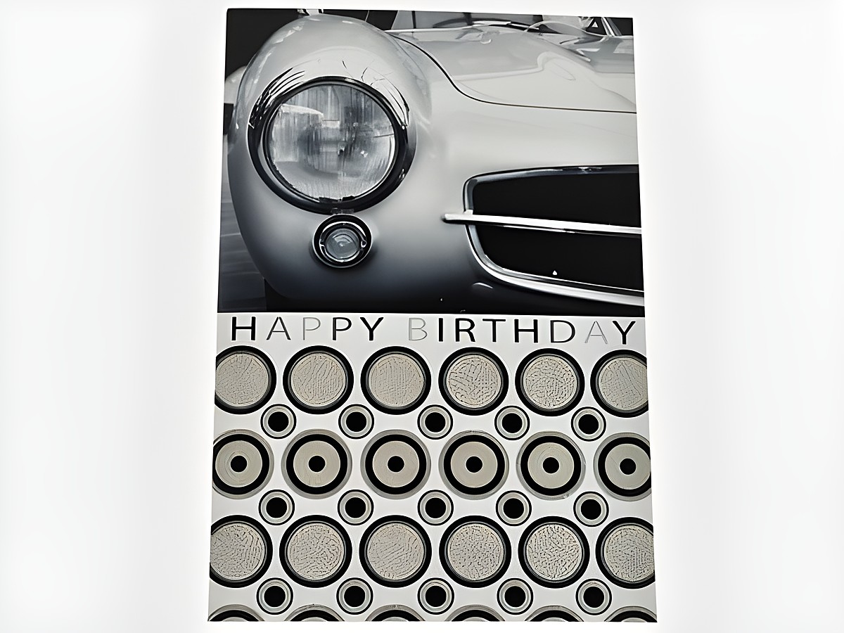 Geburtstagskarte mit einer schwarz-weißen Darstellung der Front eines Autos, verziert mit Glitzerelementen und der Aufschrift Happy Birthday, Hersteller Juwelier Harnisch.