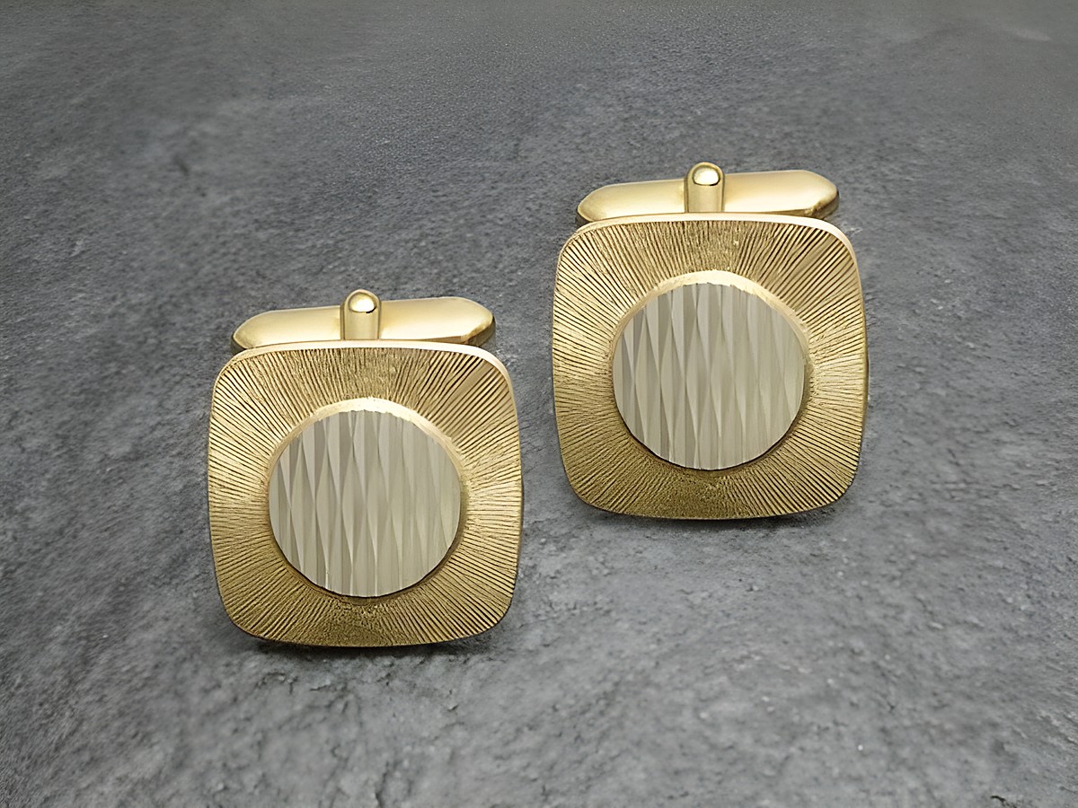 Manschettenknöpfe vergoldet im klassischen 70er Design von Juwelier Harnisch, goldfarben mit strukturiertem quadratischen Muster und rundem Zentrum. Ideal für elegante Anlässe.