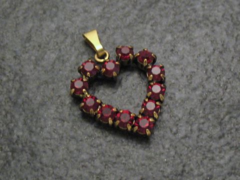 Roter Strass Anhänger im Herzen-Design, verziert mit funkelnden roten Strasssteinen und goldfarbener Öse. Perfekt für einen sexy City Look. Hersteller: Juwelier Harnisch.