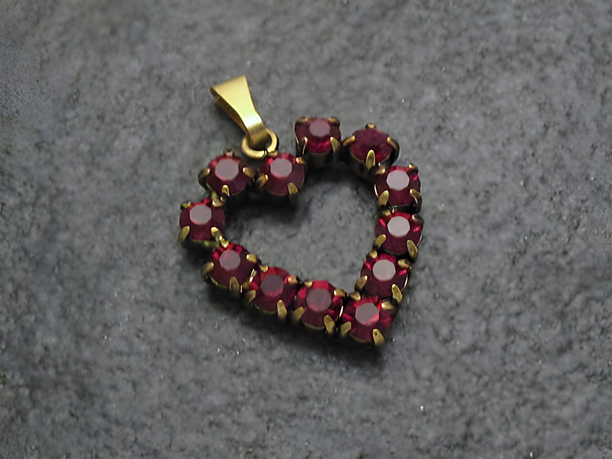 Roter Strass Anhänger im Herzen-Design, verziert mit funkelnden roten Strasssteinen und goldfarbener Öse. Perfekt für einen sexy City Look. Hersteller: Juwelier Harnisch.
