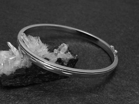 Silber Armreifen mit Diamantschliff, 4,8 mm, rhodiniert, 18 cm, präsentiert auf einem dunklen Hintergrund mit Mineralien, Hersteller Juwelier Harnisch, stilvoll und elegant.