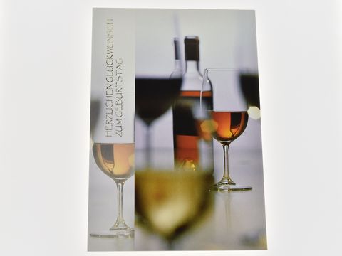Eine stilvolle Geburtstagskarte mit einer Flasche Wein und einem gefüllten Glas im Vordergrund, Hersteller Juwelier Harnisch, in sanften Farbtönen.