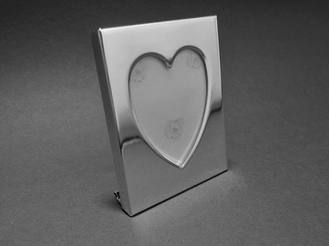 Versilberter Bilderrahmen in der Größe 7 x 5,5 cm für Herzbilder mit einer Größe von 4,1 x 3,8 cm. Der Rahmen ermöglicht eine individuelle Gravur und stammt vom Hersteller Juwelier Harnisch.