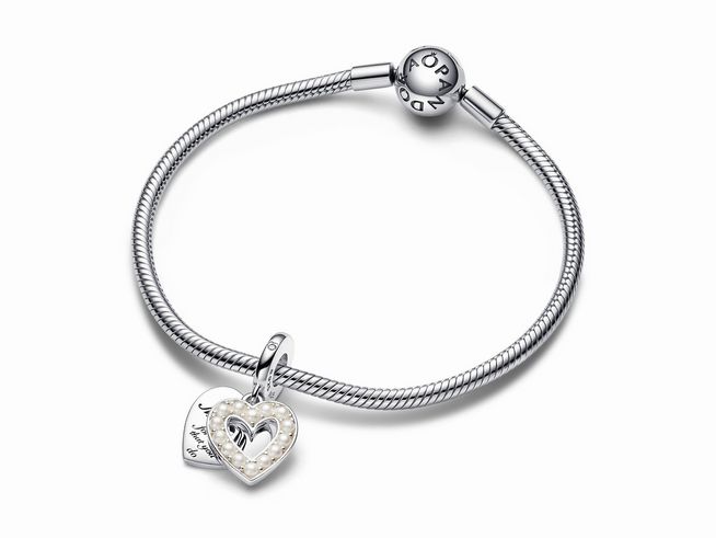Ein sterling silberner Armband mit einem doppelt charm Anhänger in Form von zwei Herzen, eines in perlmuttweiß mit eingravierter Botschaft und das andere mit einem offenen Herzen.