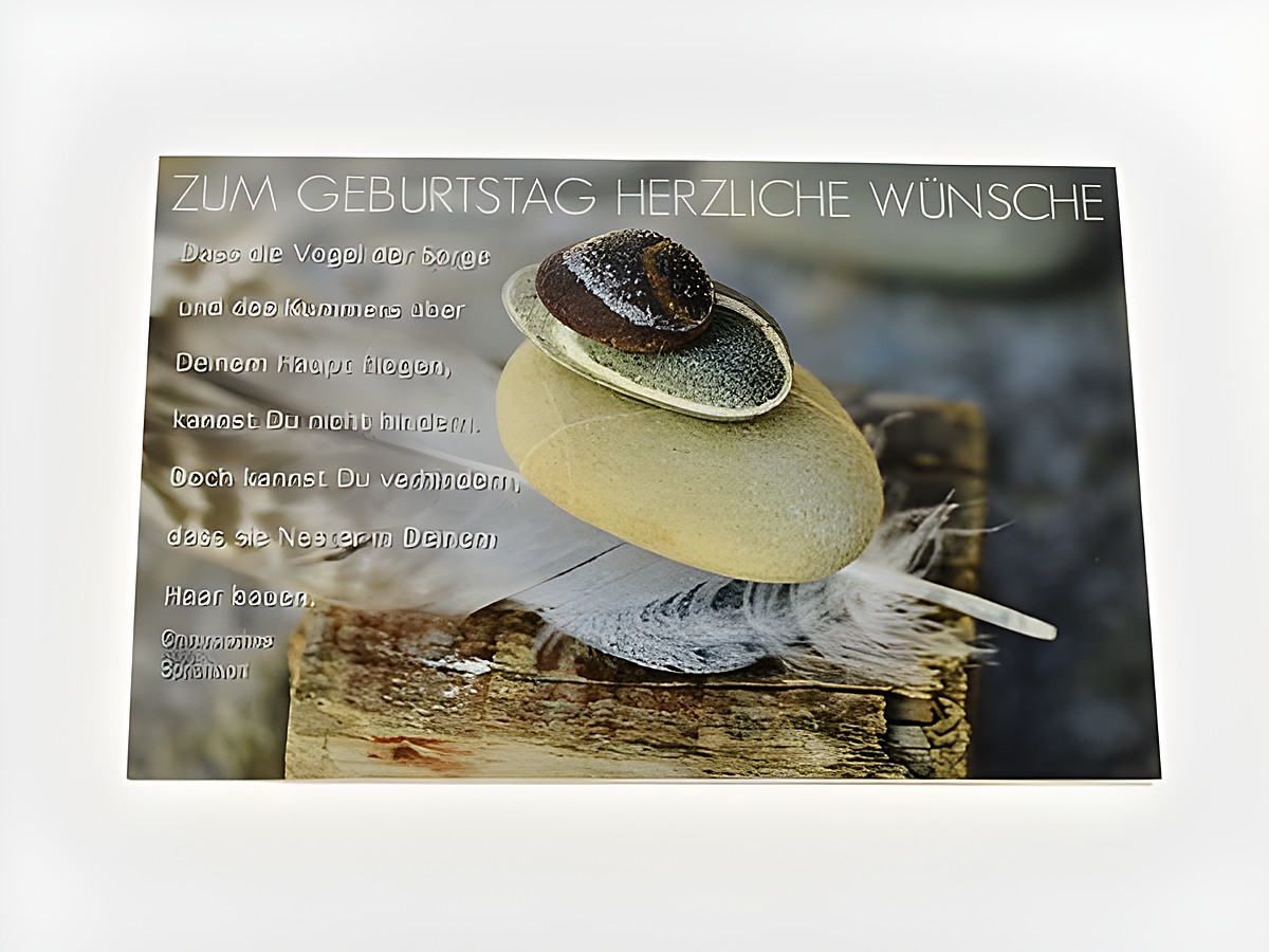 Geburtstagskarte mit einem chinesischen Sprichwort, natürlichem Hintergrund, einer Stein-Obelisken-Komposition und einer Feder, verziert mit der Aufschrift Zum Geburtstag herzliche Wünsche.