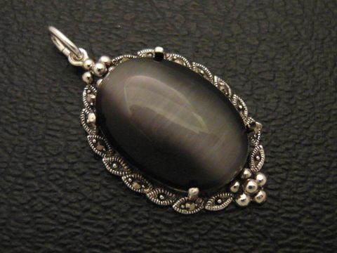 Cabochon Katzenauge schwarz Silber Medaillon Anhänger mit filigraner Umrandung, hergestellt von Juwelier Harnisch, eleganter Cabochonstein in ovaler Form.
