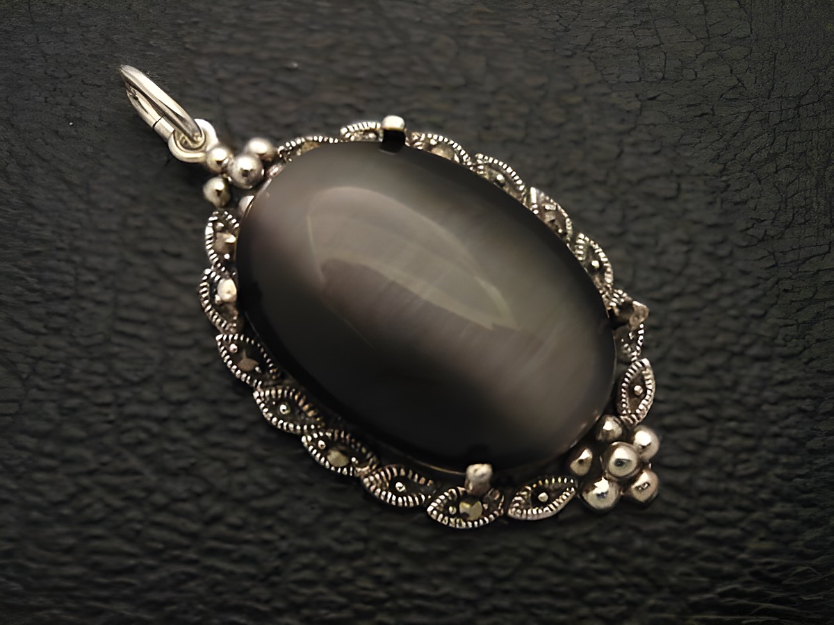 Cabochon Katzenauge schwarz Silber Medaillon Anhänger mit filigraner Umrandung, hergestellt von Juwelier Harnisch, eleganter Cabochonstein in ovaler Form.