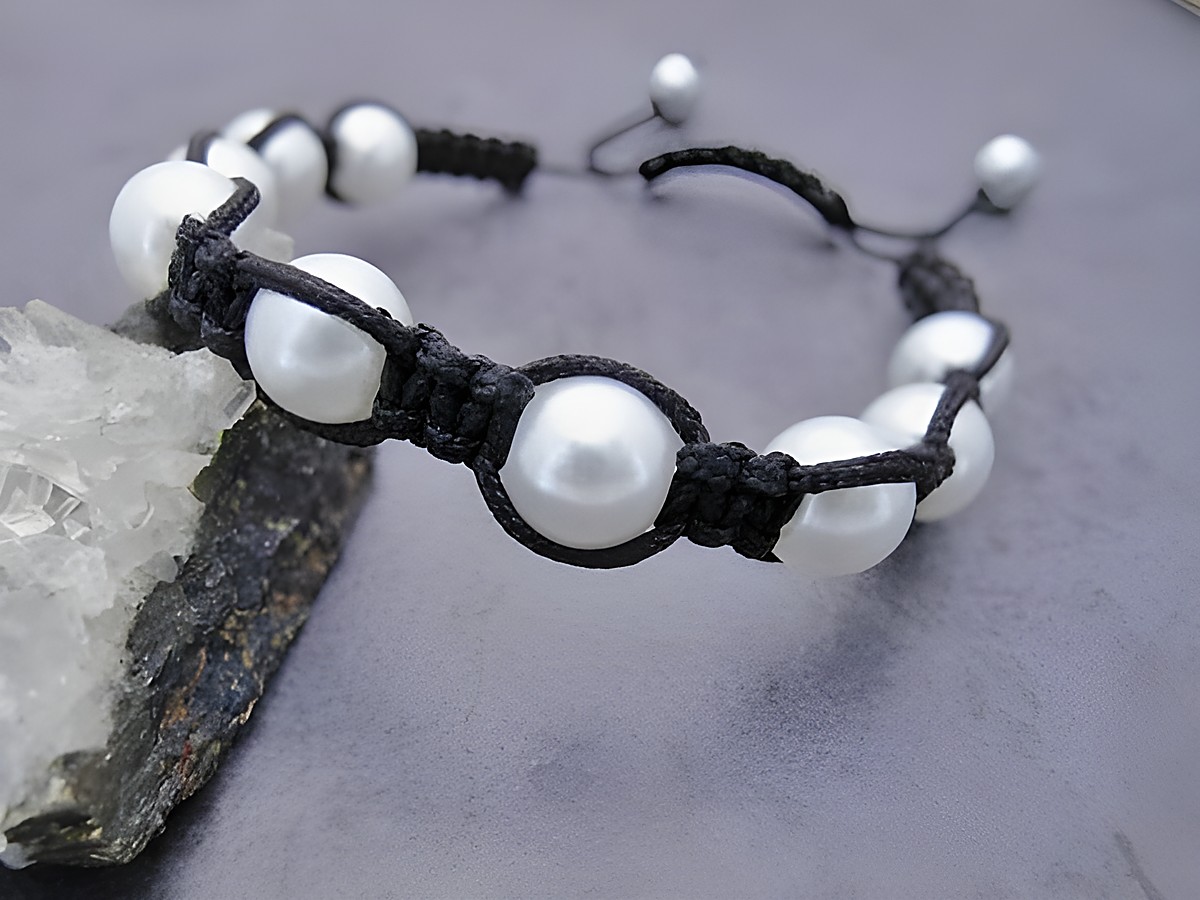 Shamballah Armband in Weiß mit synthetischen Zuchtperlen und einem schwarzen Makramee-Band, verstellbar von 18 bis 28 cm, hergestellt von Juwelier Harnisch.