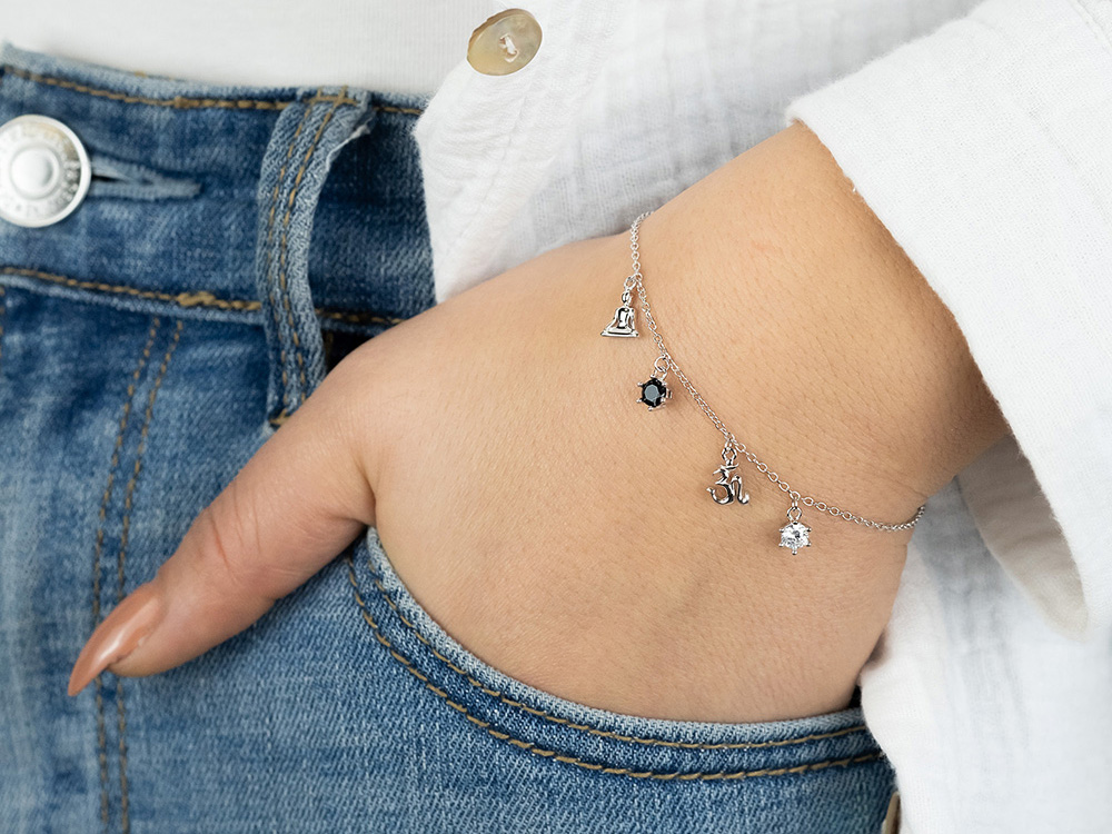 Silbernes Engelsrufer Armband mit Yin Yang Symbol und Zirkonia, Länge 17 plus 3 cm, in schöner Darstellung an einem Handgelenk, kombiniert mit lässiger Denim-Bekleidung.