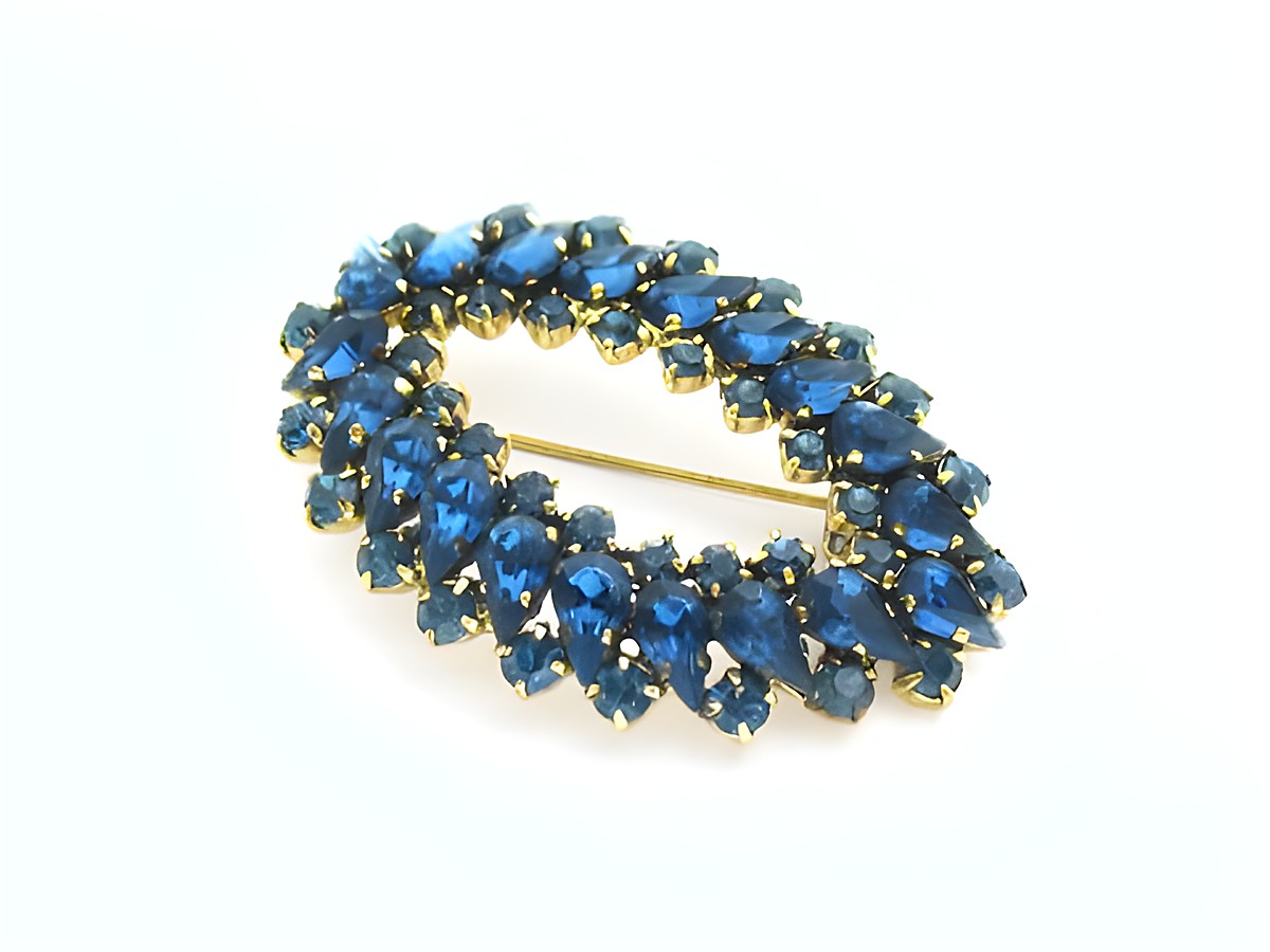 Blaue Strass Brosche im sexy City Look, oval geformt, hergestellt von Juwelier Harnisch, funkelt in verschiedenen Blautönen und verleiht jedem Outfit Eleganz und Stil.