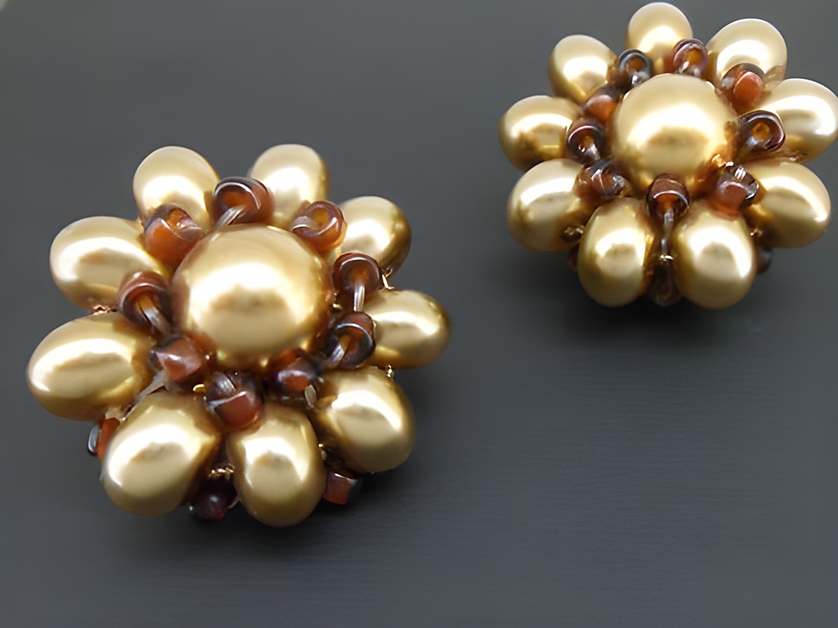 Ohrclip in honiggelb-braun mit blumigen Motiven, verziert mit goldfarbenen synthetischen Zuchtperlen, hergestellt von Juwelier Harnisch. Elegant und auffällig im Design.