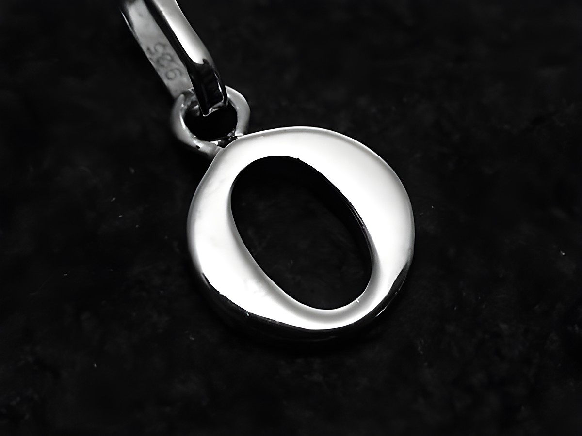 925 Sterling Silber rhodiniertes Anhänger in Form des Buchstabens O, gefertigt vom Juwelier Harnisch, glänzende Oberfläche auf schwarzem Hintergrund.