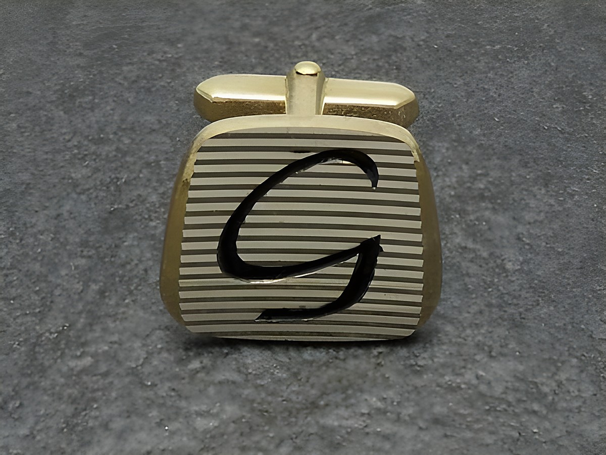 Vergoldete Manschettenknöpfe mit Initialen G, hergestellt von Juwelier Harnisch, mit eleganter Streifenoptik und künstlerisch gestaltetem Buchstaben.