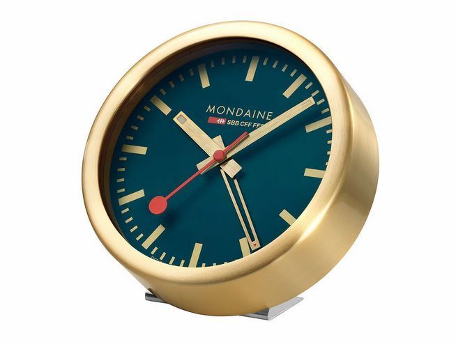 Montierte Tischuhr Mondaine A997.MCAL.46SBG.1 mit vergoldetem Aluminiumgehäuse und mattem Ozean Blau Zifferblatt, Durchmesser 12,5 cm, markante rote Zeiger für elegante Zeitmessung.