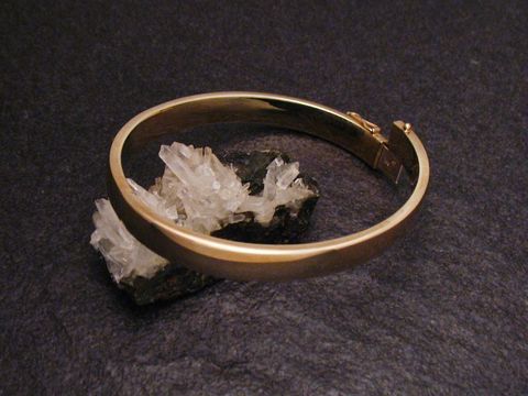 Echter goldener Armreifen mit einer Breite von 10,3 mm und einer Länge von 21 cm, hergestellt von Juwelier Harnisch, elegant auf schwarzem Untergrund präsentiert.