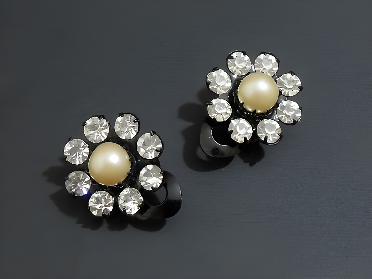 Strass Ohrclips in grazilem Design, kombiniert mit weißen und schwarzen Elementen, funkeln mit einer zentralen Perle und sind vom Hersteller Juwelier Harnisch. Ideal für elegante Anlässe.