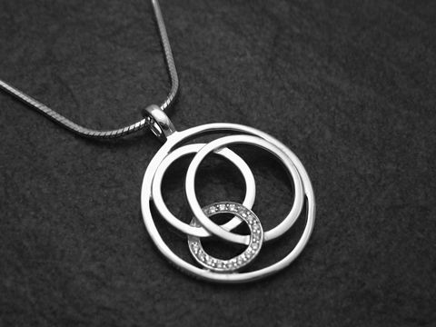 Anhänger inklusive Kette aus rhodiniertem Sterling Silber, modernes Design mit ineinandergreifenden Ringen, funkelnde Elemente, gefertigt von Juwelier Harnisch, ideal als stilvolles Schmuckstück.