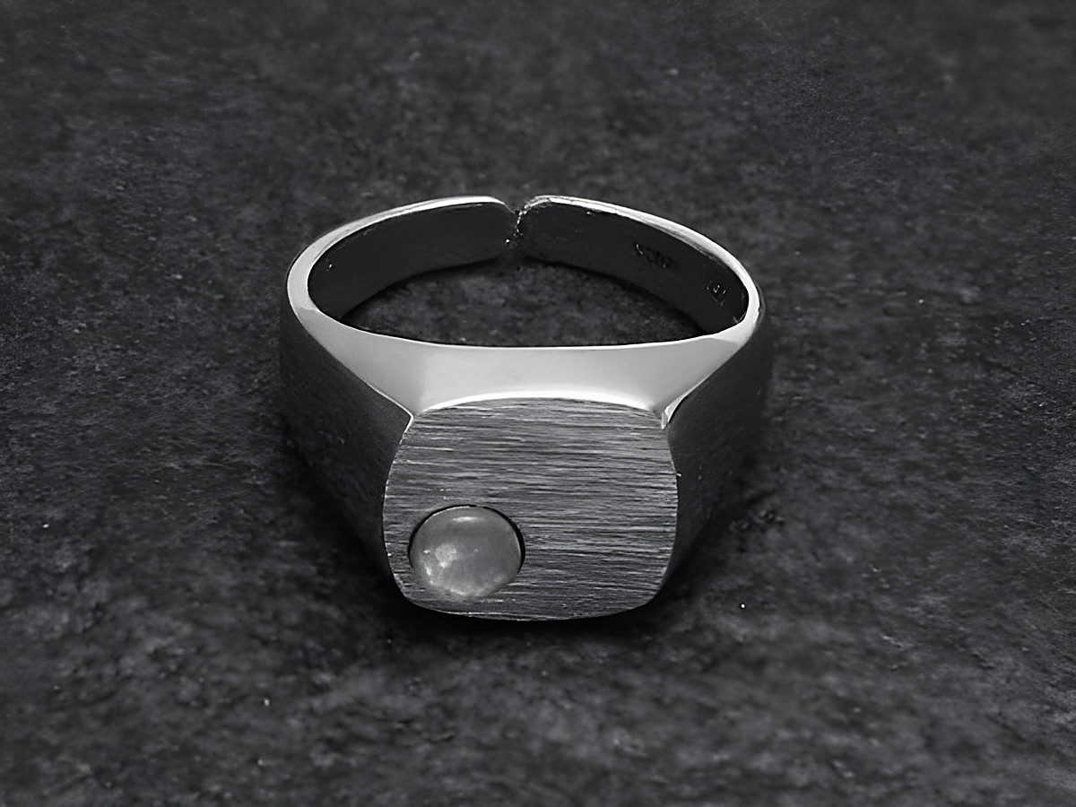 Silberring mit quadratischem, mattem Kopf und rundem, opalen Stein, größenverstellbar, rhodiniert, hergestellt von Juwelier Harnisch.