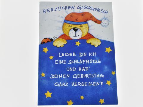 Geburtstagskarte mit einem schlafenden Teddybär in einem Schlafanzug und einer Mütze, umgeben von blauen Sternen. Text: Herzlichen Glückwunsch, leider bin ich eine Schlafmütze und hab deinen Geburtstag ganz vergessen. Hersteller: Juwelier Harnisch.