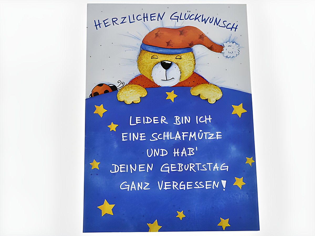 Geburtstagskarte mit einem schlafenden Teddybär in einem Schlafanzug und einer Mütze, umgeben von blauen Sternen. Text: Herzlichen Glückwunsch, leider bin ich eine Schlafmütze und hab deinen Geburtstag ganz vergessen. Hersteller: Juwelier Harnisch.