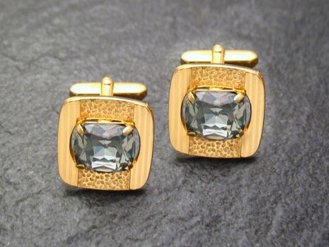 Edel vergoldete Manschettenknöpfe mit grauem Strass von Juwelier Harnisch, goldfarbenes Design mit glänzender Oberfläche und ovalem Stein, ideal für stilvolle Anlässe.