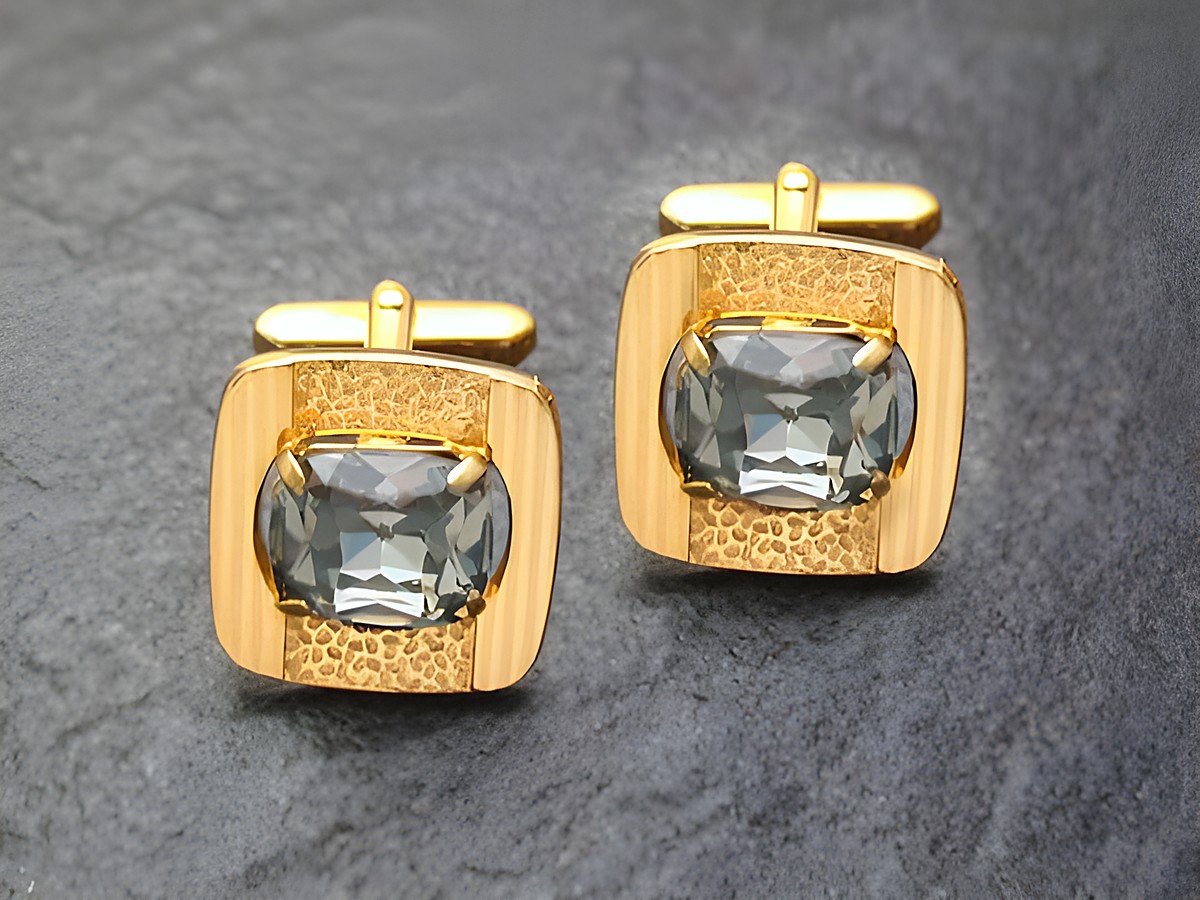 Edel vergoldete Manschettenknöpfe mit grauem Strass von Juwelier Harnisch, goldfarbenes Design mit glänzender Oberfläche und ovalem Stein, ideal für stilvolle Anlässe.