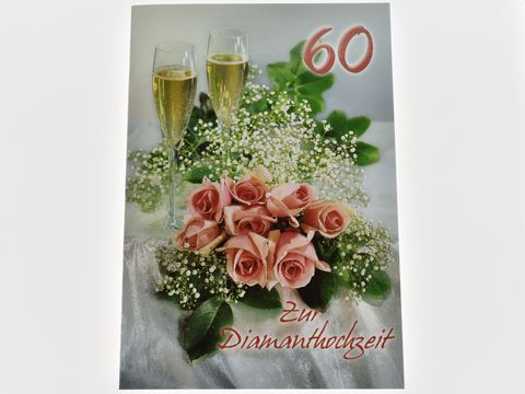 Zwei Sektgläser stehen neben einem zierenden Rosenstrauß auf einer eleganten Unterlage, dekoriert für eine Diamanthochzeit, von Juwelier Harnisch.