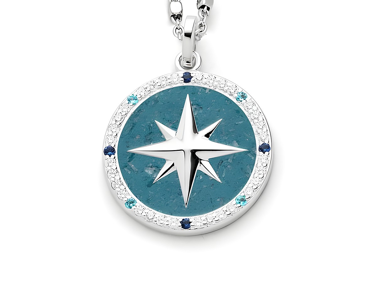 Rhodinierter Sterling Silber Anhänger in Form einer Kompassrose mit blauem Steinsand und Zirkonia. Der Anhänger hat eine zentrale silberne Sternform und ist von funkelnden Steinen umgeben.