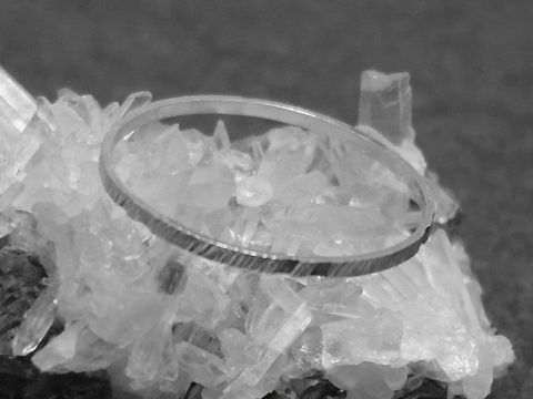 Silber Ring rhodiniert 1mm breit in Größe 60 beziehungsweise 19mm, präsentiert auf kristallinem Untergrund, Hersteller Juwelier Harnisch.