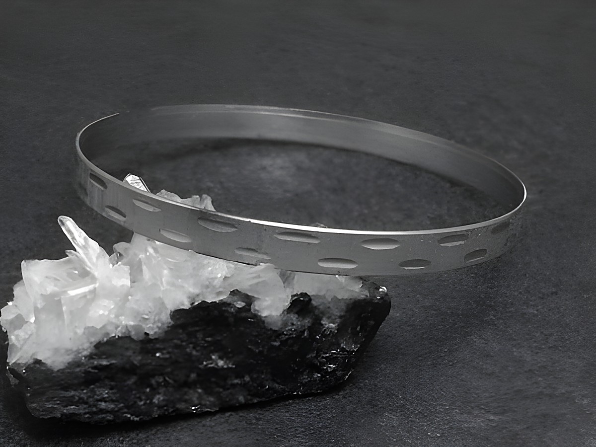 Silber Armreifen mit Diamantschliff in 6 mm, rhodiniert und 20 cm lang, präsentiert auf schwarzem Untergrund und grauem Gestein, Hersteller Juwelier Harnisch, elegant und zeitlos.