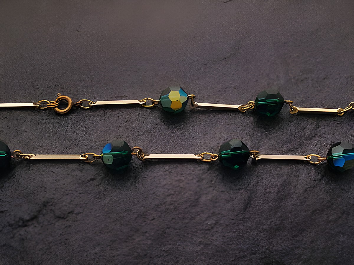 Grüne Strasskette, 54 cm lang, 10x10 mm breit, mit Facettenschliff-Steinen und goldenen Zwischenstücken, hergestellt von Juwelier Harnisch. Ideal für eleganten Schmuck.