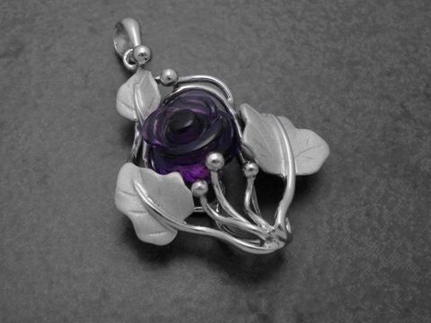 Ein teilmattierter Sterling Silber Anhänger in Form einer Rose mit Amethyst und weiteren Steinen, umgeben von stilisierten Blättern und kunstvollen Verzierungen.