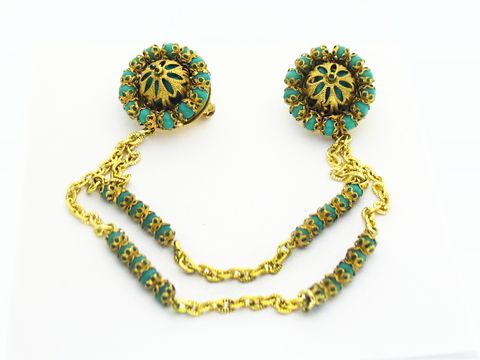 Wunderschöne Brosche in Türkis mit gefasstem Design, hergestellt von Juwelier Harnisch. Die Brosche präsentiert sich mit elegantem goldfarbenem Detail und bietet einen ansprechenden Türkis-Look.