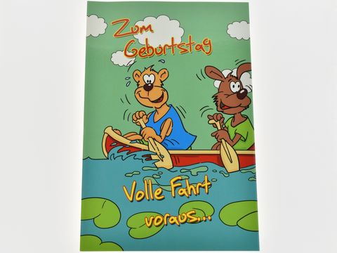 Eine bunte Geburtstagskarte zeigt einen Hund und einen Bär, die fröhlich in einem Boot paddeln. Der Hintergrund ist mit grünen Wasserlilien und blauem Wasser gestaltet.