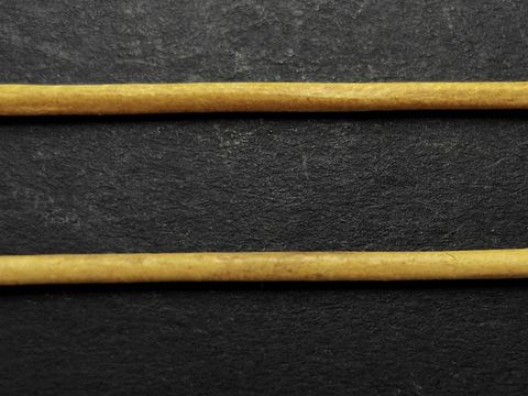 Ziegenlederkette in gelb, ca. 100 cm lang und 1,2 mm dick, hergestellt von Juwelier Harnisch, präsentiert auf schwarzem Hintergrund. Ideal für Schmuckdesign.