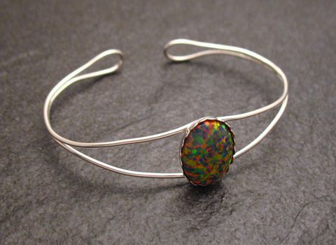 Bunter feiner Armreifen aus Sterling Silber mit einem ovalen Syn. Opal in der Mitte, Umfang 18 cm, elegantes Design von Juwelier Harnisch.
