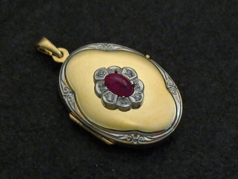 Ein bicolor Medaillon aus Gelbgold 333 mit einem ovalen Rubin Cabochon in der Mitte, umgeben von Brillanten, gefertigt vom Juwelier Harnisch.