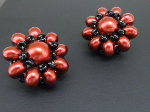 Ohrclip in rot-schwarz mit blumigem Design, verziert mit goldfarbenen Details und synthetischer Zuchtperle, hergestellt von Juwelier Harnisch, ideal für jeden Anlass.
