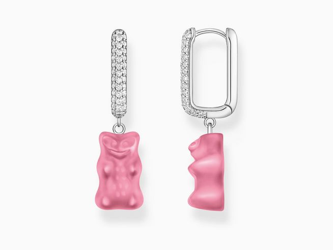 Ein Paar goldfarbene Creolen mit einem rosa-pink Gummibärchen-Anhänger, verziert mit Zirkonia-Steinen, aus der Kollektion von Thomas Sabo.