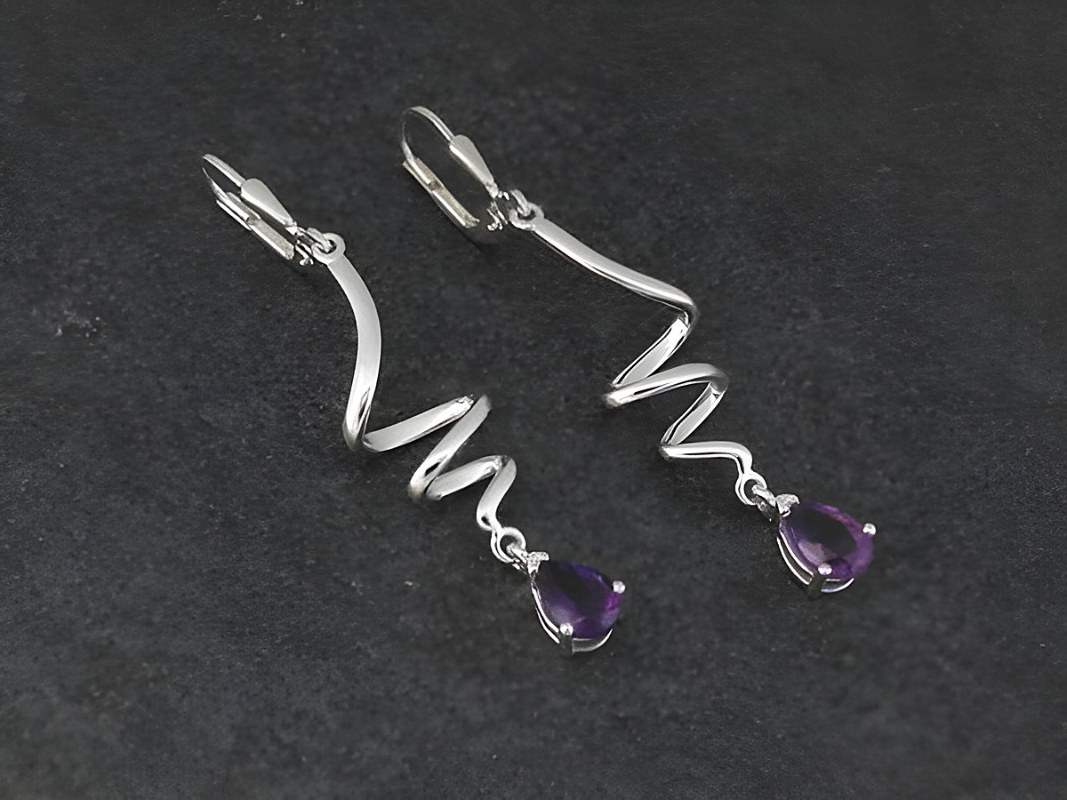 Elegante Ohrhänger aus rhodiniertem Sterling Silber mit geschwungener Form, verziert mit tropfenförmigen Amethyststeinen, ideal für stilvolle Anlässe von Juwelier Harnisch.