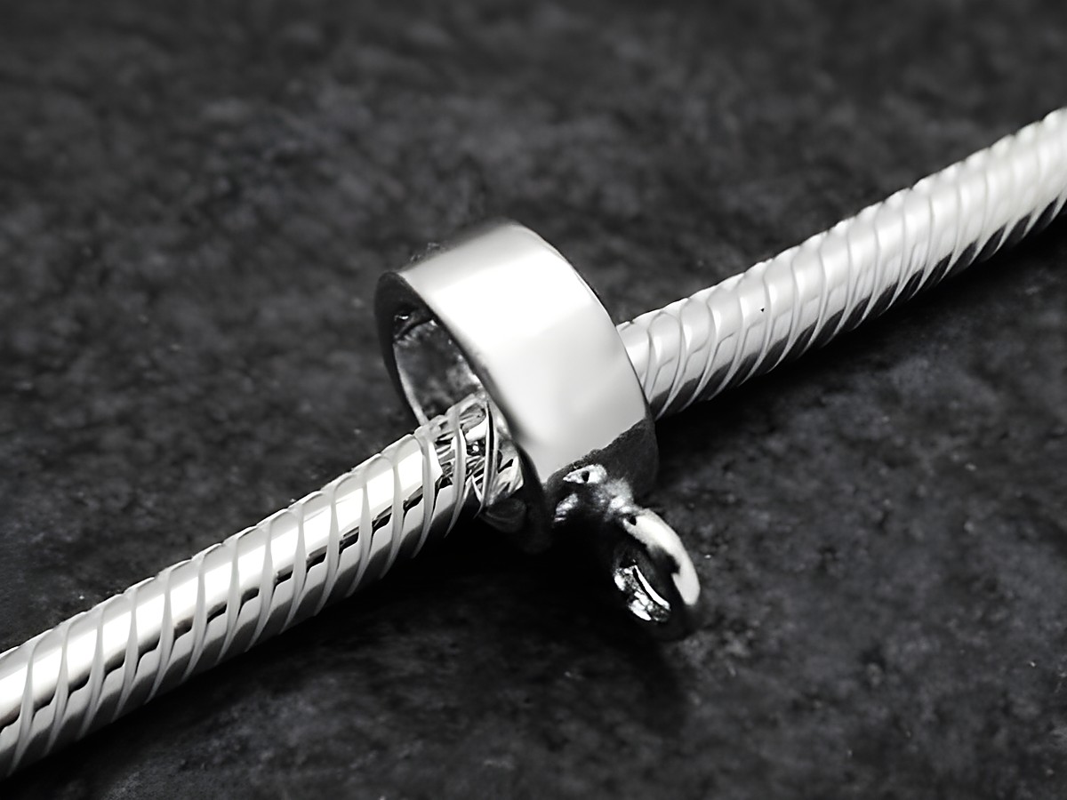 Elegance BLANKO charms Einhänger aus Sterling Silber mit 4 mm Durchmesser, glänzende Oberfläche, ideal für Schmuckstücke und Armbänder, präsentiert auf einem strukturierten Untergrund.