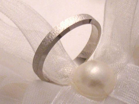 400423-0 Trauring Ehering WHITE EMOTION aus Weißgold 333 in Größe 57/18,1, Hersteller Juwelier Harnisch, auf einem zarten Untergrund mit einer Perle und einem Schleifenband präsentiert.